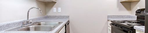 a kitchen with white cabinets and a sink and a stove