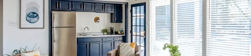 a living room with couches and chairs and a kitchen with blue cabinets