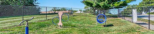 two tennis rackets in the grass in front of a fence