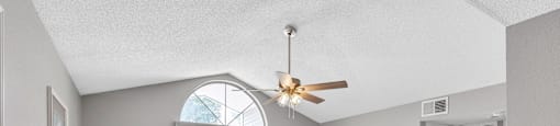 a living room with couches and chairs and a ceiling fan