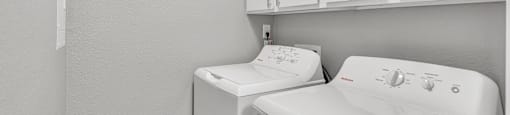 a white laundry room with a washer and dryer and white cabinets