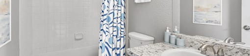 a white bathroom with a blue and white shower curtain