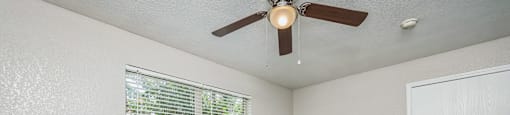 an empty living room with a ceiling fan and windows