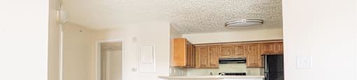 an empty living room and kitchen with wood floors