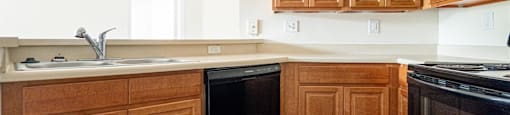 an empty kitchen with wooden cabinets and black appliances