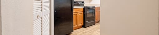 a kitchen with a black refrigerator and wooden cabinets