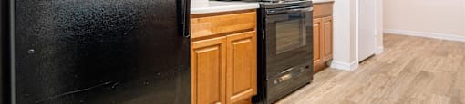 a kitchen with a black refrigerator and wooden cabinets