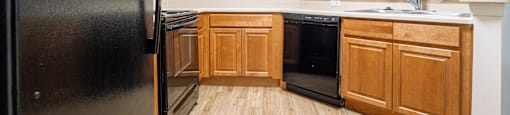 an empty kitchen with black appliances and wooden cabinets