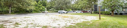 a volleyball court in a park with cars parked in a parking lot