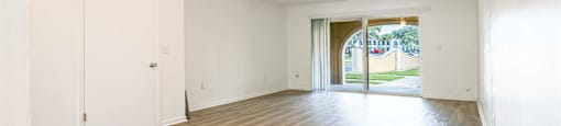 an empty living room with wood flooring and a door to a patio