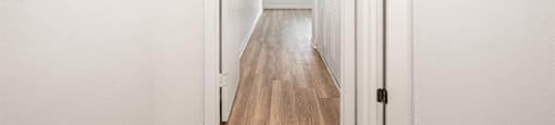 a hallway with white walls and wood floors and a white door