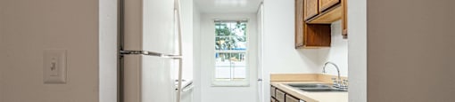 a kitchen with white appliances and wooden floors and a window