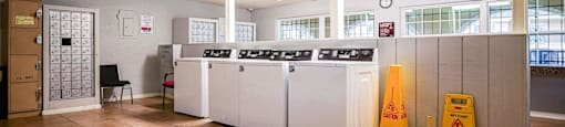 a laundry room with four washing machines and a yellow caution sign