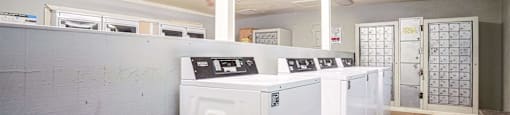 a row of washers and dryers in an empty laundry room