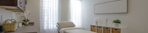 A room with a massage table and a window with curtains.