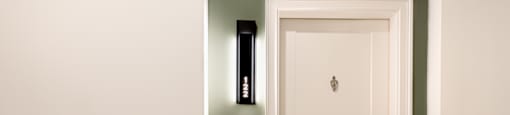 A white door with a brass handle is set in a green wall.