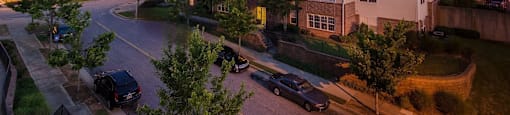 Apartment complex with cars parked in front and trees in the foreground.