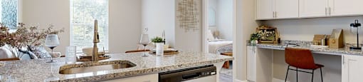 A kitchen with a sink, dishwasher, and a counter with a chair.