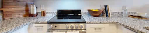 A kitchen with a black stove top oven and white cabinets.