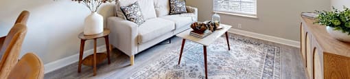 A living room with a couch, a coffee table, and a painting on the wall.