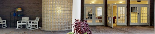A patio with a white chair and a black planter.