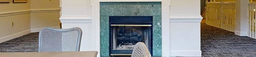A painting hangs above a fireplace in a room with a table and chairs.
