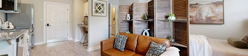 A living room with a brown couch and a painting on the wall.