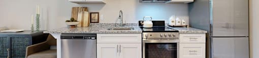 A modern kitchen with white cabinets and stainless steel appliances.