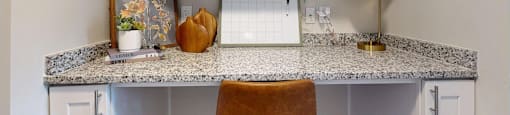A kitchen counter with a white fridge and a brown chair.