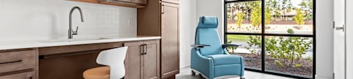 A kitchen with brown cabinets and a blue chair.