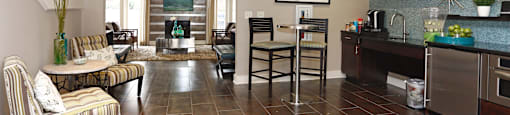 A living room with a striped couch and a kitchen area with a refrigerator and oven.