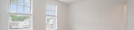 A room with a ceiling fan and two windows.