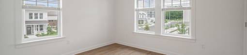 A room with a ceiling fan and two windows.