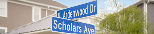 A street sign for Ardenwood Dr and Scholars Ave stands in front of a house.