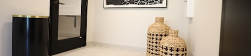 A black and white abstract painting hangs on a white wall above two woven baskets.