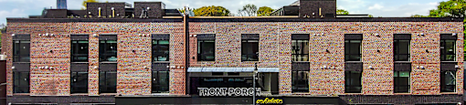 The front porch is a modern building with a black facade and a yellow sign on the top left corner.