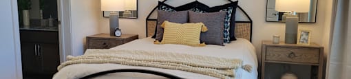 A bed with a white comforter and a pillow with a blue design on it.