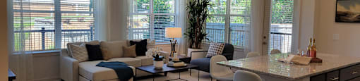 A living room with a couch, chair, and a table with a plant on it.