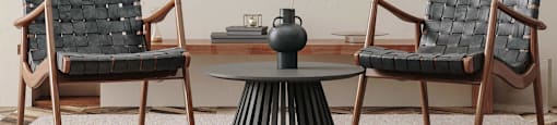Two chairs and a table with a vase on it.