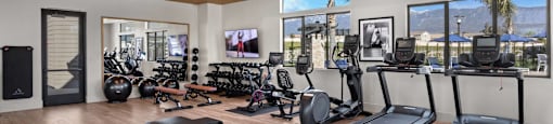 a gym with a lot of exercise equipment and windowsat Westbury Apartments, Rancho Cucamonga, California