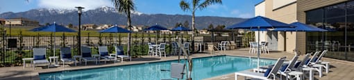 a swimming pool with chairs and umbrellas and mountains in the backgroundat Westbury Apartments, Rancho Cucamonga, California