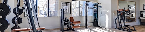 a gym with exercise equipment and windows at the district flats apartments  at Westbury Apartments, Rancho Cucamonga, California