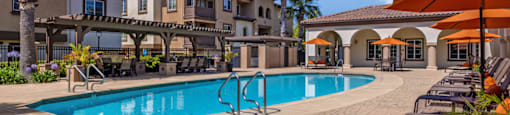 A swimming pool surrounded by lounge chairs and umbrellas.
