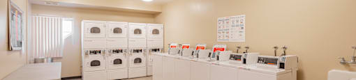 a laundry room with washers and dryers and a counter with sinks and laundry at International Village UCR Student Housing, Riverside, CA 92507