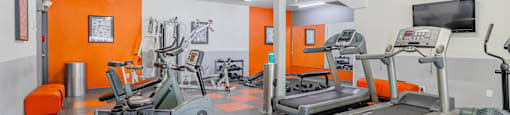 a gym with a lot of machines and chairs and a tv at International Village UCR Student Housing, Riverside, 92507