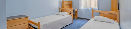 a bedroom with two beds and a desk and a chair at International Village UCR Student Housing, Riverside, CA