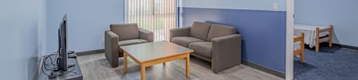 a living room with couches and a coffee table and a tv at International Village UCR Student Housing, Riverside