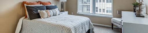 a bedroom with a bed, dresser and a large window