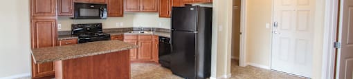 a kitchen with a black refrigerator freezer next to a stove top oven