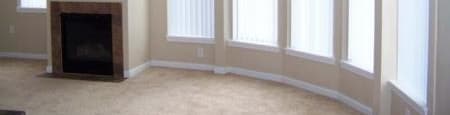 an empty living room with a fireplace and large windows